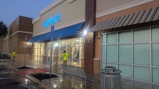 JPC crew member rinsing the Carter's storefront sidewalk during off-hours cleaning at Hammock Landing in Palm Bay, FL