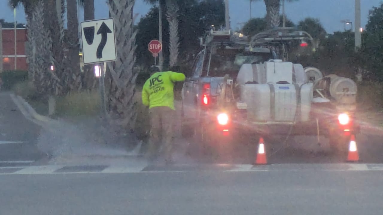 JPC technician pressure washing a sidewalk next to the work trailer at Hammock Landing in Palm Bay, FL