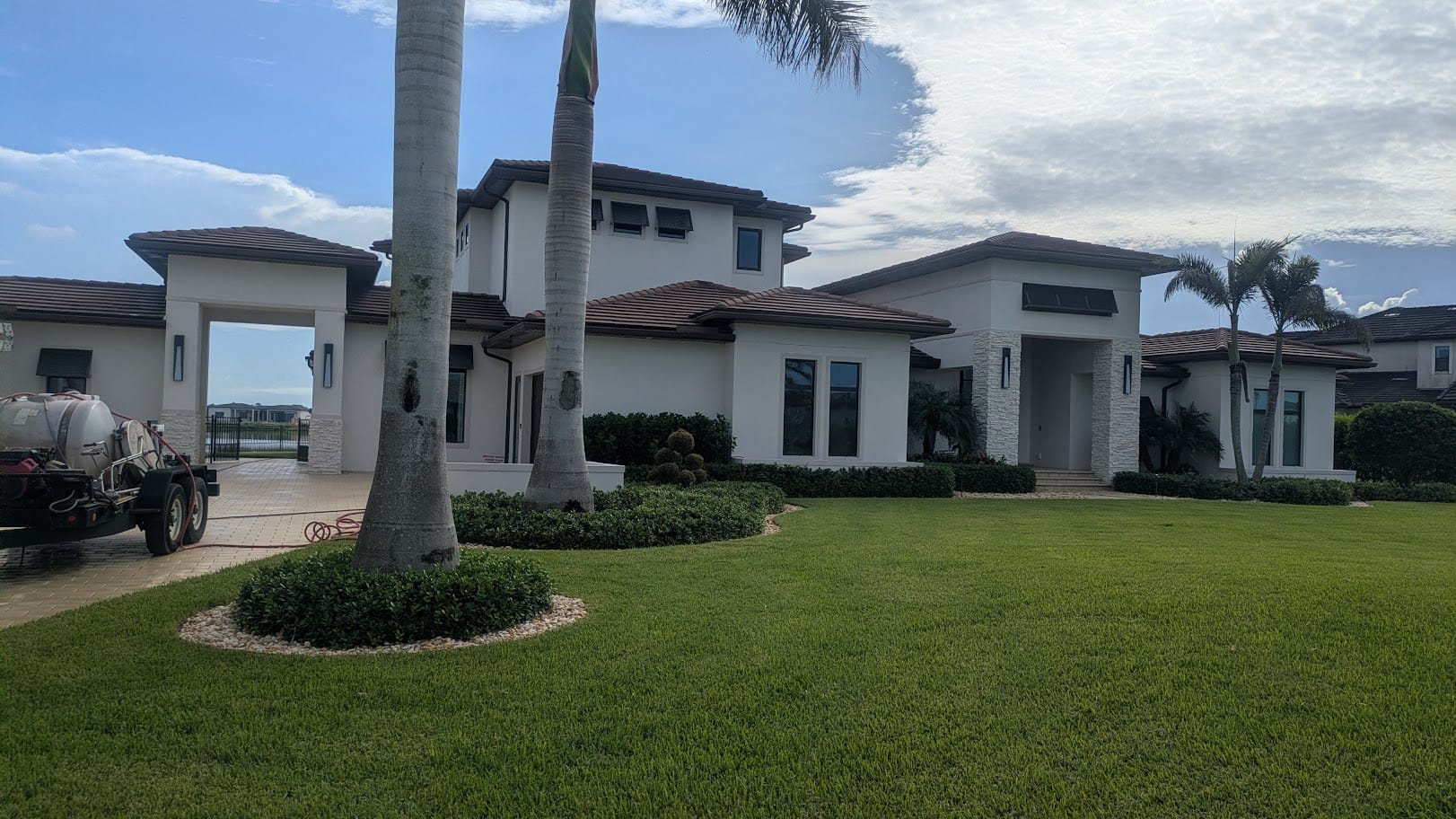 White lakefront estate in Viera, FL with the JPC wash trailer set up on the paver driveway
