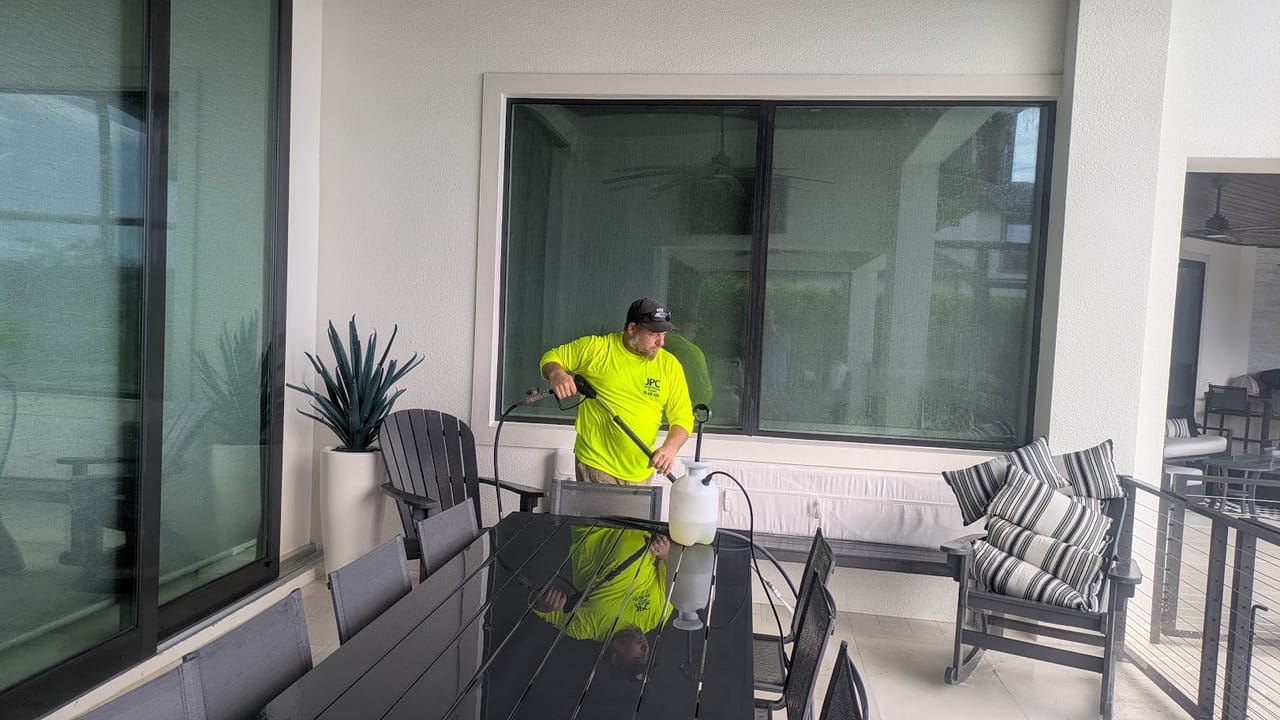 JPC crew member applying soft wash solution to patio windows and screens at a Viera, FL lakefront home