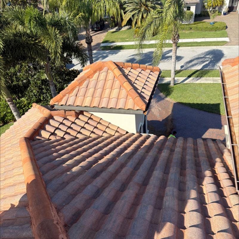 JPC crew member working a soft wash roof cleaning on a terracotta tile roof in Viera, FL