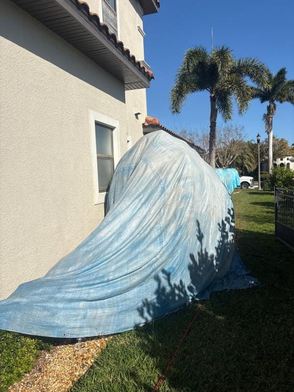 Plants and shrubs covered with protective tarps during a JPC soft wash roof cleaning in Viera, FL